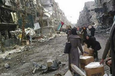 Women with United Nations Relief and Works Agency (UNRWA) aid packages in the besieged Palestinian refugee camp of Yarmouk in Damascus (photo taken on a mobile phone)
